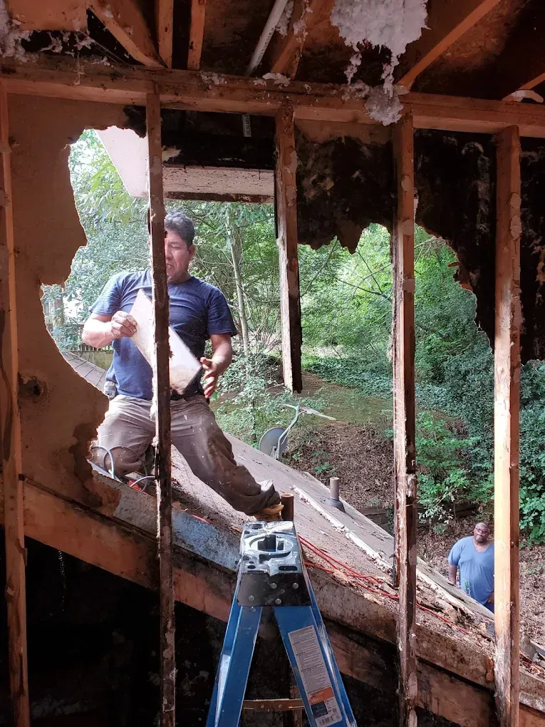 Technician cleaning smoke-stained walls during home restoration